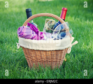 Outdoor-Picknick-Korb mit Wein in Flaschen und Gläser auf Rasen Stockfoto