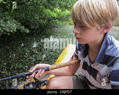 Ein kleiner Junge Fische vom Boot im See Stockfoto