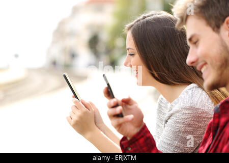 Glückliche Teen paar mit Smartphones in einem Bahnhof, während sie warten Stockfoto