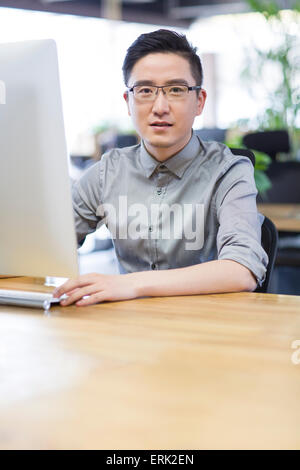 Junger Mann mit Computer im Büro Stockfoto
