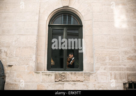 Brautpaar küssen im Fenster Stockfoto