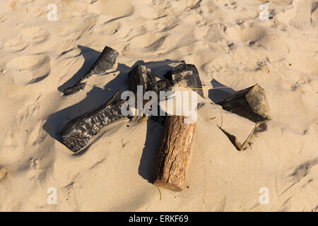 Bleibt ein kleines Lagerfeuer mit verbranntem Holz und Sand am Strand Stockfoto