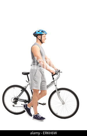 Voller Länge Profil Schuss ein aktiver junger Mann mit einem blauen Sportschutzhelm auf dem Kopf ein Fahrrad schieben und lächelnd Stockfoto