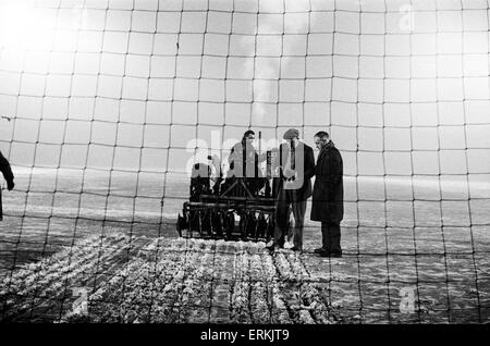 Liverpools Trainer rief Bill Shankly in Herrn John Flut von Queensferry, Experte für Boden bauen, um den Boden für Mittwoch die Krawatte Wiederholung Pokalspiel gegen den FC Burnley bereit. Hier ist er neben dem Traktor gezogen Scheibe Harrower durchschneiden die vereisten Tonhöhe an der Anfield Road abgebildet. Dies löst das Eis, bevor es von einem Bulldozer aufgehoben ist. 27. Januar 1963. Stockfoto