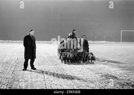 Liverpools Trainer rief Bill Shankly in Herrn John Flut von Queensferry, Experte für Boden bauen, um den Boden für Mittwoch die Krawatte Wiederholung Pokalspiel gegen den FC Burnley bereit. Hier ist er neben dem Traktor gezogen Scheibe Harrower durchschneiden die vereisten Tonhöhe an der Anfield Road abgebildet. Dies löst das Eis, bevor es von einem Bulldozer aufgehoben ist. 27. Januar 1963. Stockfoto