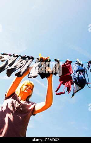 hängen die Wäsche trocknen Frau Dame weiblichen Smalls Socken Linie pegging Heringe Wäsche mühsam Womans Arbeit nie Stockfoto