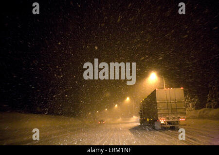 Ein semi-LKW stapft durch Schneefall in der Nacht.  Truckee, Kalifornien. Stockfoto