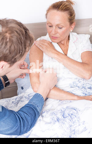 Mann, der Pflaster am Arm der Frau Stockfoto
