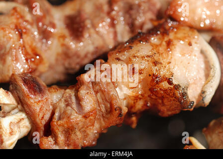 Saftige Scheiben von Fleisch mit Soße vorbereiten auf Feuer Stockfoto