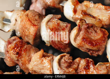 Saftige Scheiben von Fleisch mit Soße vorbereiten auf Feuer Stockfoto
