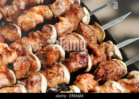 Saftige Scheiben von Fleisch mit Soße vorbereiten auf Feuer Stockfoto