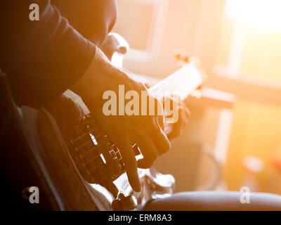 Männliche Hand auf der akustischen Gitarre zu spielen. Close-up. Stockfoto