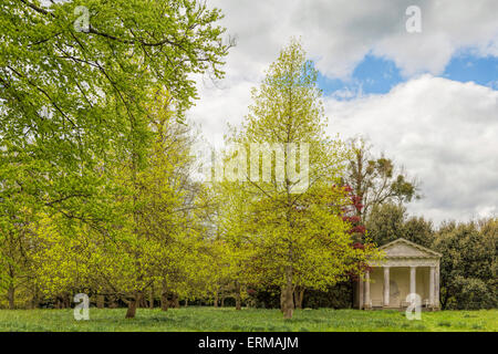 Üppiger Vegetation im Frühjahr und Blick auf den dorischen Tempel in der Vergnügen Garten Petworth House in West Sussex, England, UK. Stockfoto