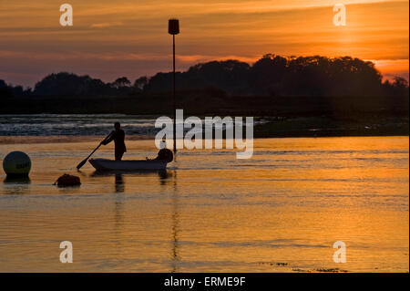 Eine Braut und Bräutigam setzen Sie die Segel mit ihm das Boot mit einem Ruder in einem magischen Sonnenuntergang Lenkung Stockfoto