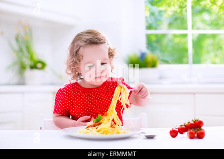 Kinder essen Nudeln. Gesundes Mittagessen für Kinder. Kleinkind Kind essen Spaghetti Bolognese in einer weißen Küche zu Hause. Vorschulkind Kind Stockfoto