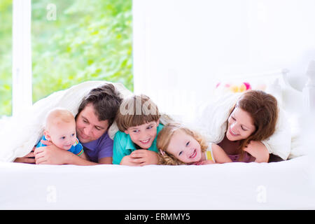 Glückliche Großfamilie, junge Eltern mit drei Kindern, lachen, junge, Kleinkind Mädchen und entzückende kleine Baby tragen bunte Schlafanzüge Stockfoto