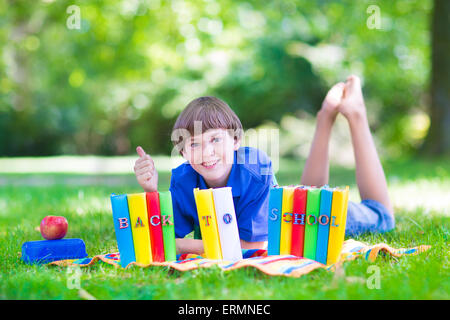 Glücklich lachende Jugendlicher Student junge im Garten Schule Bücher zu lesen und mit gesunder Snack, zurück zum Schulkonzept Stockfoto