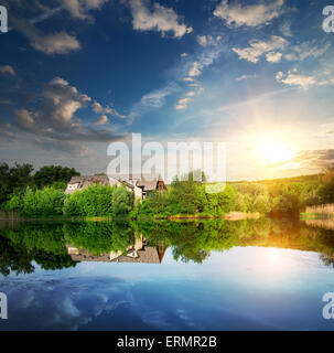 Sonnenuntergang über Dorf in der Nähe von dem ruhigen Fluss Stockfoto