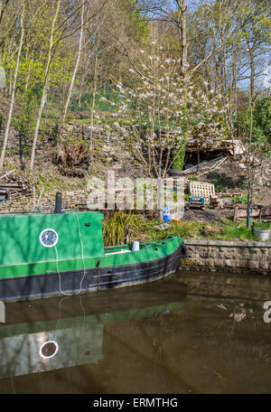 Ein Narrowboat vertäut neben einigen unordentlich Gartenartikel Stockfoto