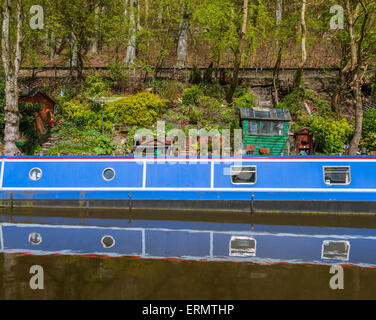 Ein Narrowboat vertäut neben einigen unordentlich Gartenartikel Stockfoto