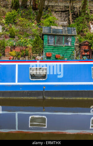 Ein Narrowboat vertäut neben einigen unordentlich Gartenartikel Stockfoto