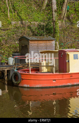 Ein Narrowboat vertäut neben einigen unordentlich Gartenartikel Stockfoto