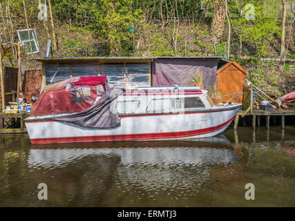 Ein Narrowboat vertäut neben einigen unordentlich Gartenartikel Stockfoto