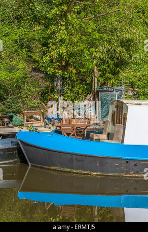 Ein Narrowboat vertäut neben einigen unordentlich Gartenartikel Stockfoto