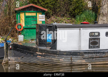 Ein Narrowboat vertäut neben einigen unordentlich Gartenartikel Stockfoto