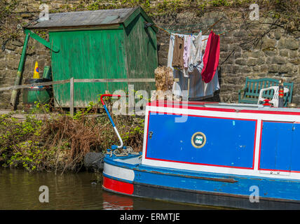 Ein Narrowboat vertäut neben einigen unordentlich Gartenartikel Stockfoto