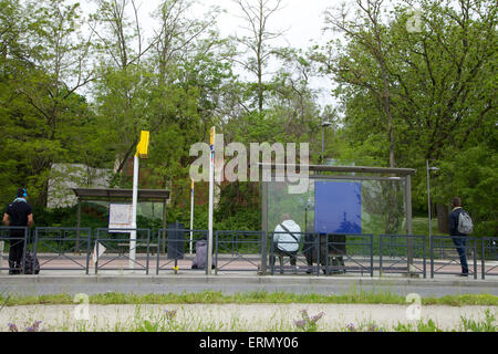 Jugendliche warten Bus an der Bushaltestelle nach der Schule Stockfoto