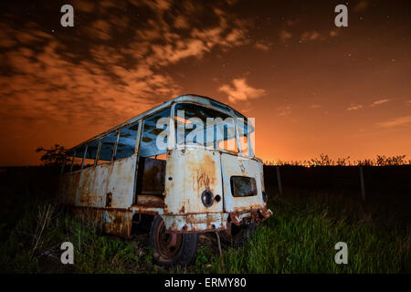 Alten rostigen Bus in ungewöhnliche Licht bei Nacht Himmel und Sterne Hintergrund Stockfoto