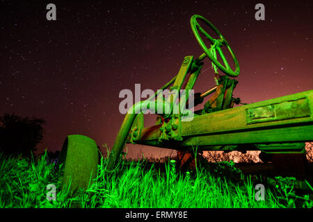 Lauf der Zeit Konzept - alten rostigen Traktor in sternenklaren Nacht auf ungewöhnliche Licht Stockfoto