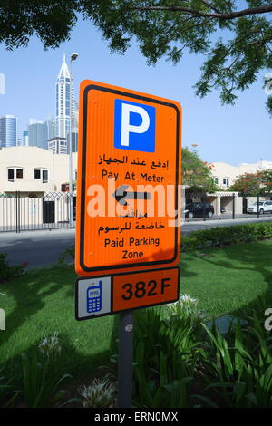 Ein Zeichen in Arabisch und Englisch informiert Fahrer, gebührenpflichtige Parkplätze am Messgerät, Media City, Dubai, Vereinigte Arabische Emirate Stockfoto