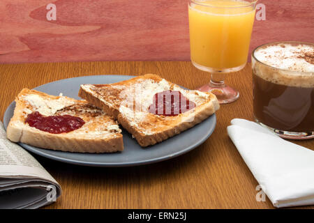 ein romantisches zubereitetes Frühstück mit Toast mit Butter und Marmelade in Form eines Herzens und einer Kaffee-Nexto ein Newpaper und eine Serviette Stockfoto