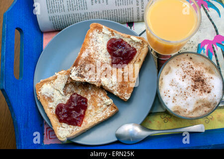 ein romantisches zubereitetes Frühstück mit Toast mit Butter und Marmelade in Form eines Herzens und einer Kaffee-Nexto ein Newpaper und eine Serviette Stockfoto