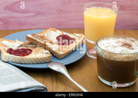 ein romantisches zubereitetes Frühstück mit Toast mit Butter und Marmelade in Form eines Herzens und einer Kaffee-Nexto ein Newpaper und eine Serviette Stockfoto