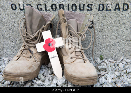 Nicht zu vergessen... ein paar der modernen britischen desert Kampfstiefel auf ein Denkmal des 1. Weltkrieges mit einem Kreuz und Mohn. Stockfoto