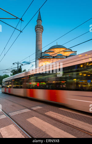 Verschwommene Straßenbahn vorbei in der Abenddämmerung in der Nähe einer Moschee in Divanyolu Street im Stadtteil Sultanahmet, Istanbul, Türkei Stockfoto