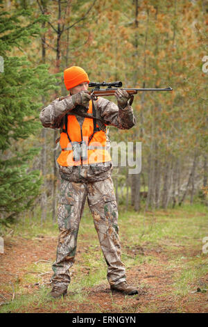 Erwachsenen Jäger mit dem Ziel Hirsch Gewehr im Wald Stockfoto