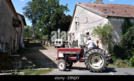 Ein französischer Bauer treibt seinen Traktor auf den Hof Stockfoto