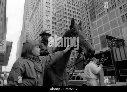 Chicago, IL, 14. Dezember 1996: ein kleines Mädchen ist das Pferd von einem berittenen Polizisten an der Michigan Avenue streicheln. Stockfoto