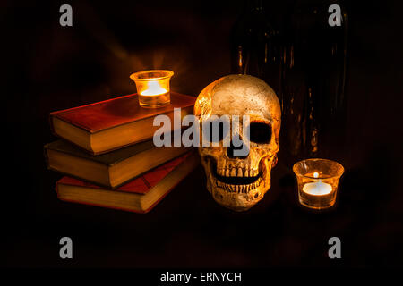 Ein Vintage Schädel sitzt neben einem Stapel von alten Romane und Weinflaschen; Bild erstellt mit einem leichten Maltechnik Stockfoto