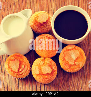 Nahaufnahme von einem Porzellan-Topf mit Milch, eine Porzellantasse mit Kaffee und ein Haufen von Muffins auf einem rustikalen Holztisch Stockfoto