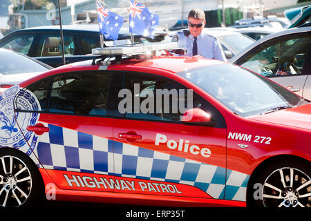 Neu Südwales Polizist steht seinem Autobahn Polizei Streifenwagen im Palm Beach Sydney, geschmückt mit zwei australische Flaggen Stockfoto