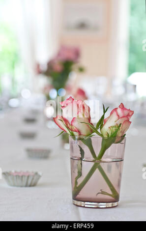 weiße Rosen mit roten Fransen Blüten in einem Glas auf einem Party-Tisch Stockfoto