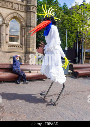 Middlesbrough, UK. 6. Juni 2015. 25. jährliche Middlesbrough Mela multikulturelle Veranstaltung 6. Juni 2015 ein Alter Mann auf einem Sitz ein Stelzenläufer Walker schaut gekleidet wie ein riesiger Storch, warten auf die Eröffnung "Geschichten der Welt" Parade Kredit führen: Peter Jordan NE/Alamy Live News Stockfoto