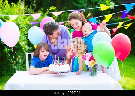 Glückliche Großfamilie mit drei kids genießen-Geburtstags-Party mit Kuchen Kerzen im Garten geschmückt mit Luftballons und Fahnen wehen Stockfoto