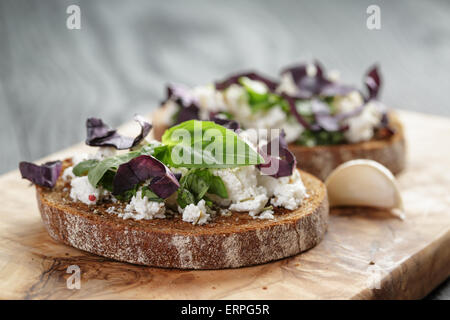 Roggen-Sandwich oder Bruschetta mit Ricotta, Kräutern und Basilikum Stockfoto