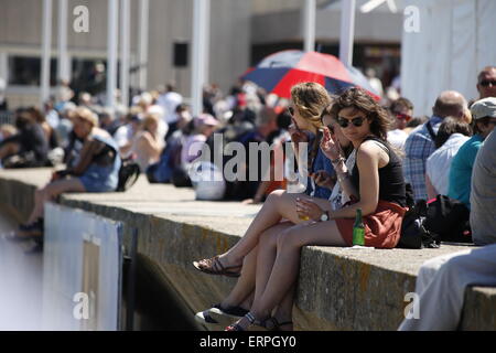 Eine Gruppe von Frauen das Rauchen von Zigaretten und Alkohol zu trinken, sitzend auf einer Wand in einer Lage direkt am Meer, Arromanche, Normandie, Frankreich Stockfoto